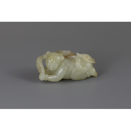 193 - A Pale Celadon Jade Boy, 18th century,  finely carved with the smiling reclining boy holding a leafy... 