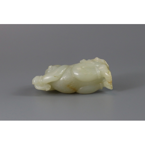 193 - A Pale Celadon Jade Boy, 18th century,  finely carved with the smiling reclining boy holding a leafy... 