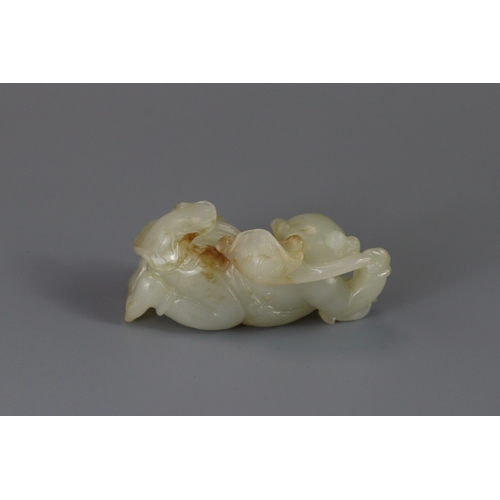 193 - A Pale Celadon Jade Boy, 18th century,  finely carved with the smiling reclining boy holding a leafy... 