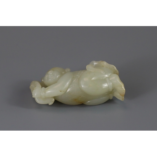 193 - A Pale Celadon Jade Boy, 18th century,  finely carved with the smiling reclining boy holding a leafy... 