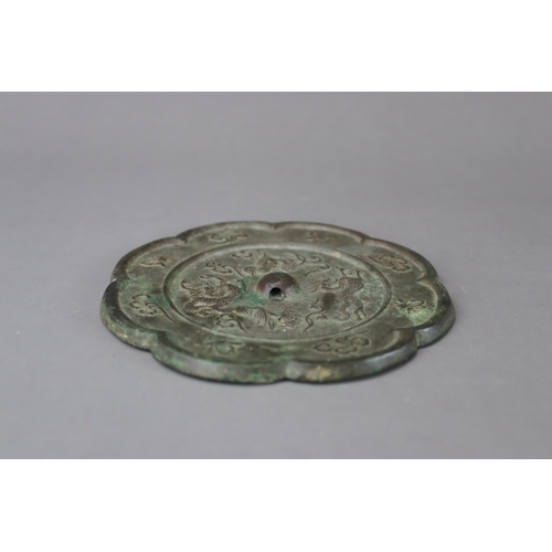 212 - A Bronze Mirror, Tang dynasty,  with petal lobed rim, the central medallion crisply moulded around t... 