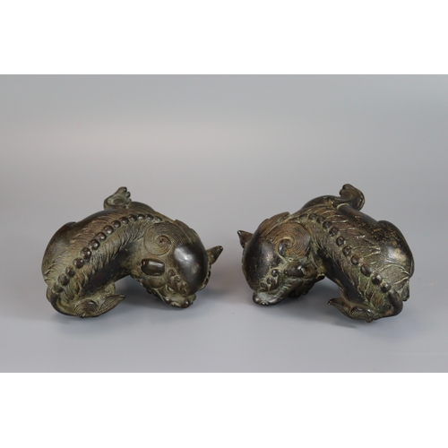 461 - A Pair of Bronze Buddhist Lions, Qing dynasty, the seated beasts with heads turned in ferocious snar... 