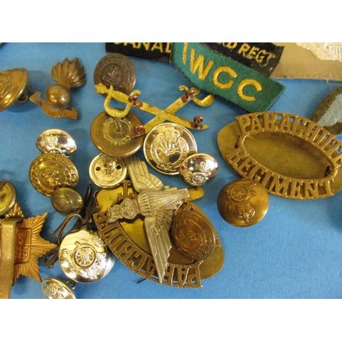 211 - A parcel of military cloth and metal badges and buttons