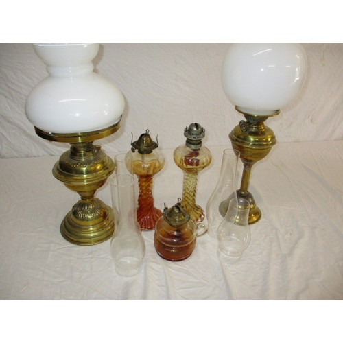 329 - A quantity of vintage oil lamps to include some shades and chimneys