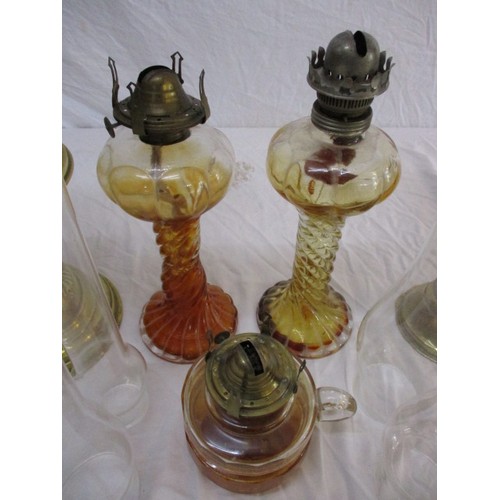 329 - A quantity of vintage oil lamps to include some shades and chimneys