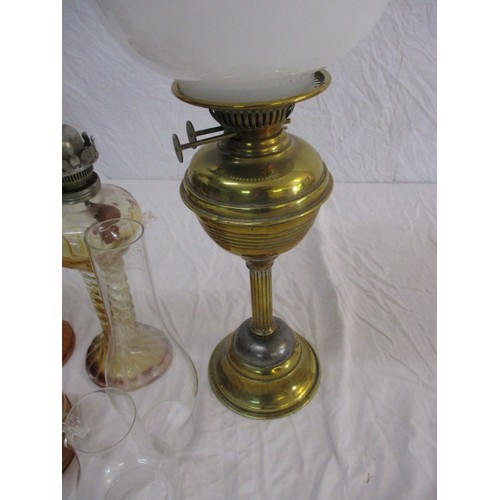 329 - A quantity of vintage oil lamps to include some shades and chimneys