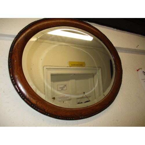 7 - A vintage oak framed oval wall mirror with bevelled glass, having one small spot to mirror and gener... 