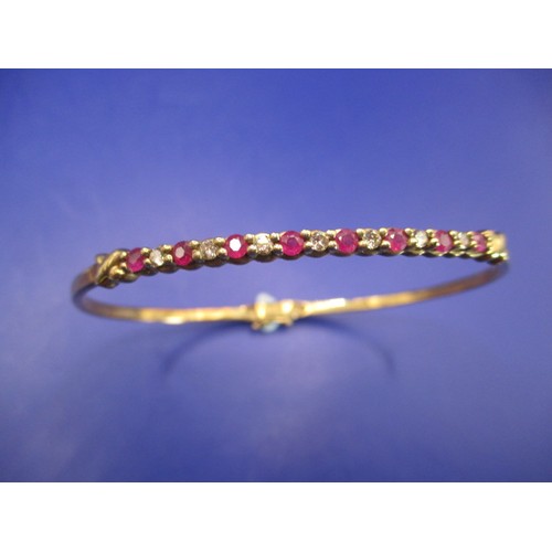 66 - A 9ct yellow gold diamond and ruby bangle, approx. weight 7.9g, approx. diameter 6cm in good pre-own... 