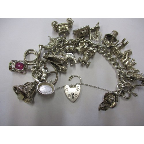 114 - A silver and white metal charm bracelet, approx. weight 90.5g having multiple charms in pre-owned co... 