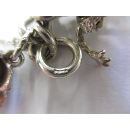 114 - A silver and white metal charm bracelet, approx. weight 90.5g having multiple charms in pre-owned co... 