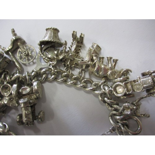 114 - A silver and white metal charm bracelet, approx. weight 90.5g having multiple charms in pre-owned co... 