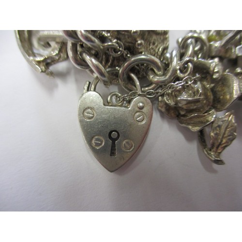 114 - A silver and white metal charm bracelet, approx. weight 90.5g having multiple charms in pre-owned co... 