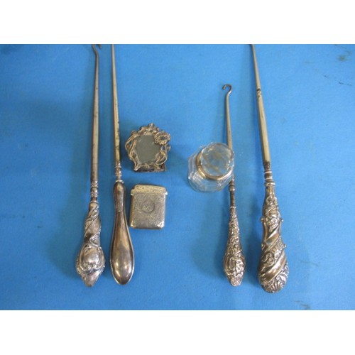 122 - A parcel of silver and silver mounted items, to include a vesta case and button hooks, all in used c... 