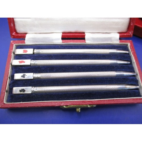 137 - A boxed set of 4 sterling silver propelling pencils, each with card suits to top, some loss to ename... 