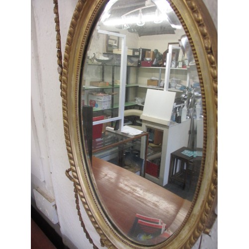 81 - A 19th century gilt framed mirror, the oval panel being bevelled glass, having some age-related dama... 