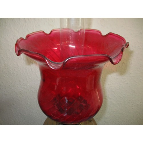 121 - A vintage oil lamp with red glass shade and chimney