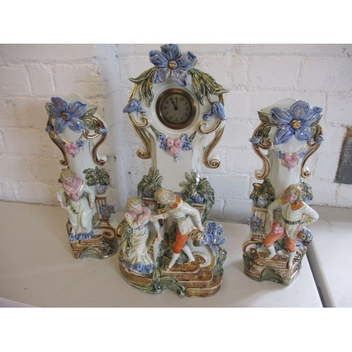 289 - A 19th century German porcelain mantle garniture of 2 vases and a clock stand. Clock not working. In... 