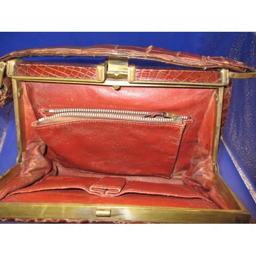 189 - An early 20th Century Crocodile skin handbag. Clasp works well, with age related ware and a split to... 