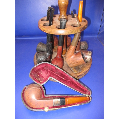 134 - A vintage pipe rack and pipes, to include a silver collared example, some damages and all in used co... 