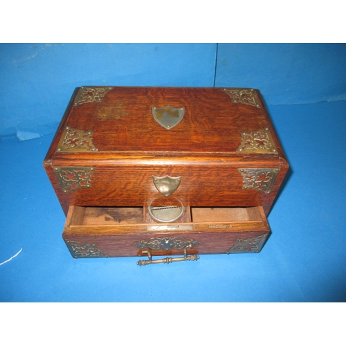 285 - An early 20th century oak desk top stationary box, the top opening is operated via the base drawer, ... 