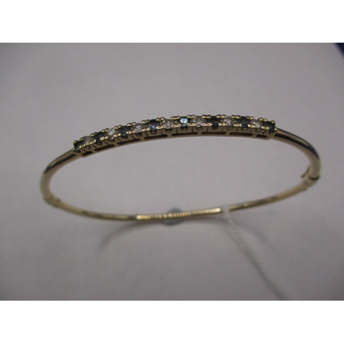 71 - A 9ct yellow gold bangle with diamonds and sapphires, approx. weight 5.4g in pre-owned condition wit... 