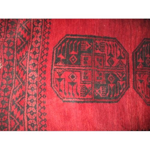 329 - A vintage hand woven Afghan wool rug, approx. size 216x125cm, having a rich red ground with black ge... 