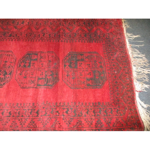 329 - A vintage hand woven Afghan wool rug, approx. size 216x125cm, having a rich red ground with black ge... 