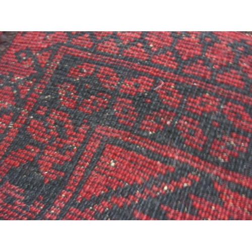 329 - A vintage hand woven Afghan wool rug, approx. size 216x125cm, having a rich red ground with black ge... 