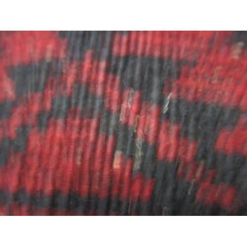 329 - A vintage hand woven Afghan wool rug, approx. size 216x125cm, having a rich red ground with black ge... 