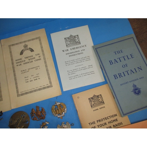 216 - A parcel of WWII military related items, to include metal badges and Civil defence public informatio... 