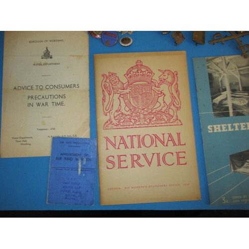 216 - A parcel of WWII military related items, to include metal badges and Civil defence public informatio... 