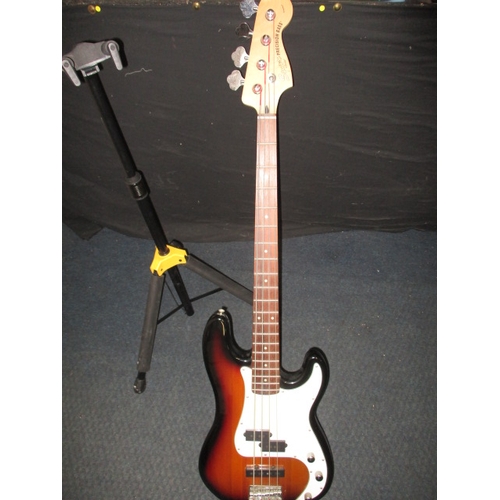 308 - A Squier by Fender precision electric bass guitar, with a Hercules guitar stand. In pre-owned condit... 