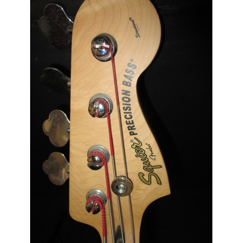 308 - A Squier by Fender precision electric bass guitar, with a Hercules guitar stand. In pre-owned condit... 