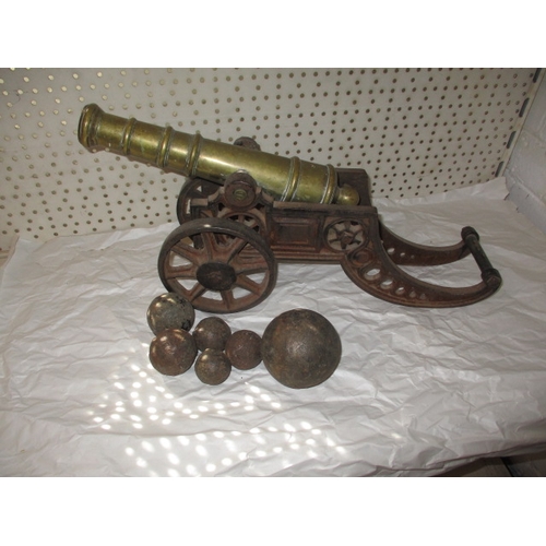 296 - A vintage brass and iron table top cannon and a quantity of iron balls, all in used condition, appro... 