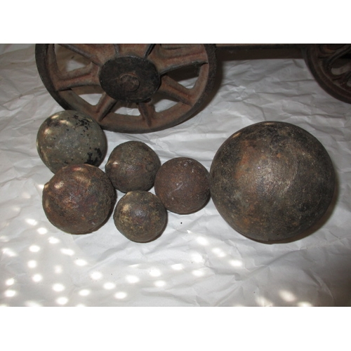 296 - A vintage brass and iron table top cannon and a quantity of iron balls, all in used condition, appro... 