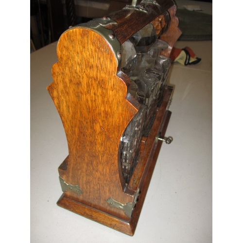 301 - An early 20th century oak 3 bottle tantalus, having key and working lock, in good used condition wit... 