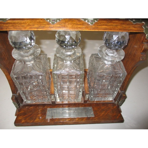 301 - An early 20th century oak 3 bottle tantalus, having key and working lock, in good used condition wit... 