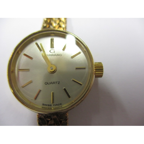 84 - A 9ct yellow gold ladies wrist watch with integral gold strap, marked Garrard, in original box, requ... 