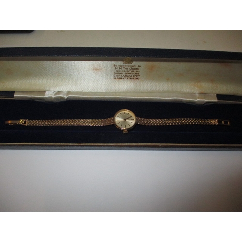 84 - A 9ct yellow gold ladies wrist watch with integral gold strap, marked Garrard, in original box, requ... 