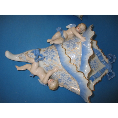 318 - A pair of vintage porcelain wall pockets, with blue swags, ribbons and cherubs, some damages but dis... 