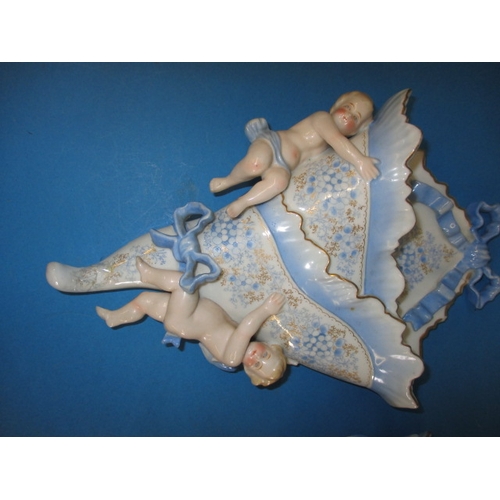 318 - A pair of vintage porcelain wall pockets, with blue swags, ribbons and cherubs, some damages but dis... 