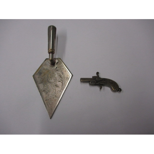 145 - A vintage white metal pistol charm with working mechanism and a decorative plated trowel, in useable... 