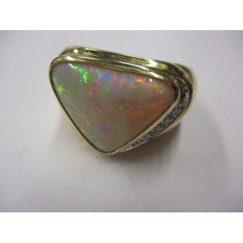 34 - An 18ct yellow gold ring with a large trillion cut Coober Pedy opal and diamonds to one flank, appro... 