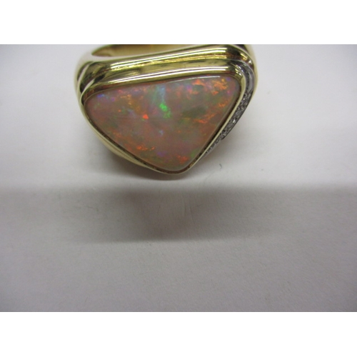 34 - An 18ct yellow gold ring with a large trillion cut Coober Pedy opal and diamonds to one flank, appro... 