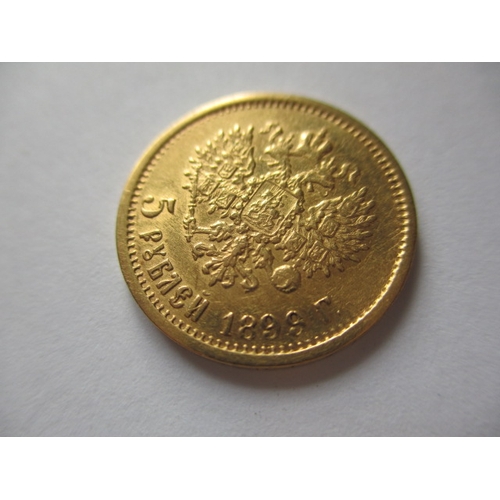 83 - A Russian gold five rouble coin, with Nicholas II dated 1899,  a circulated coin with very fine defi... 