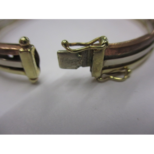 44 - A 9ct tri-colour gold bangle, approx. weight 14g, clasp opening clip broken