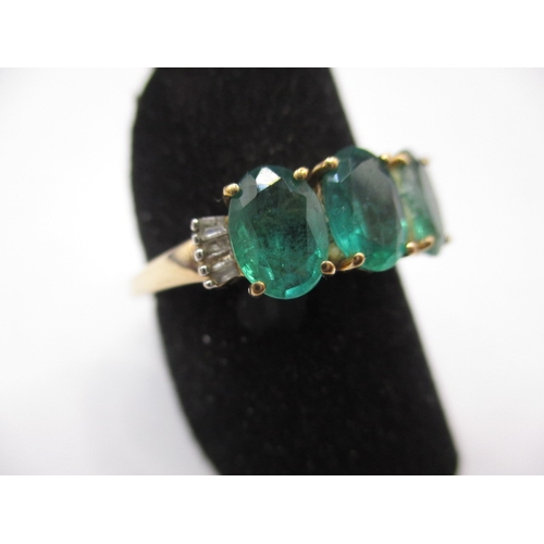 14 - A 9ct yellow gold, 3 stone Zambian emerald dress ring with diamond set shoulders, approx. ring size ... 