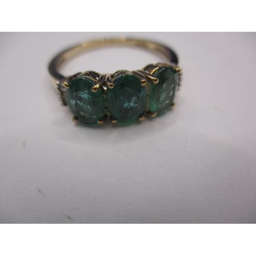 14 - A 9ct yellow gold, 3 stone Zambian emerald dress ring with diamond set shoulders, approx. ring size ... 