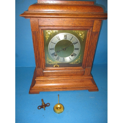 211 - A vintage American made oak cased mantle clock, with key and pendulum, runs when wound but would ben... 