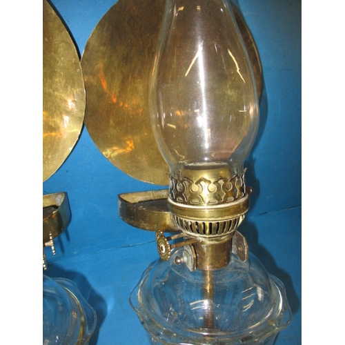 293 - Two vintage oil burning wall lights, with glass reservoirs and brass mounts, having use-related mark... 